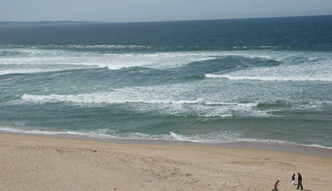 Photograph of a rip current — note the calm darker channel of water between breaking waves on either side